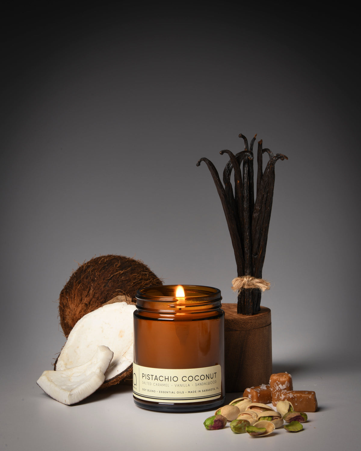 Amber glass candle jar with lit wick, with pistachio and coconut pieces