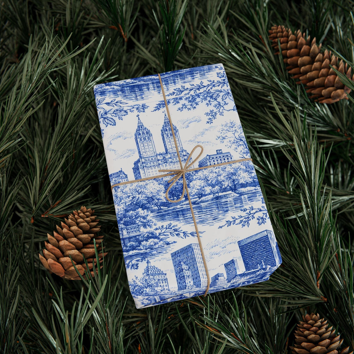 Blue-and-white toile wrapping paper gift wrap on top of pine branches with bow