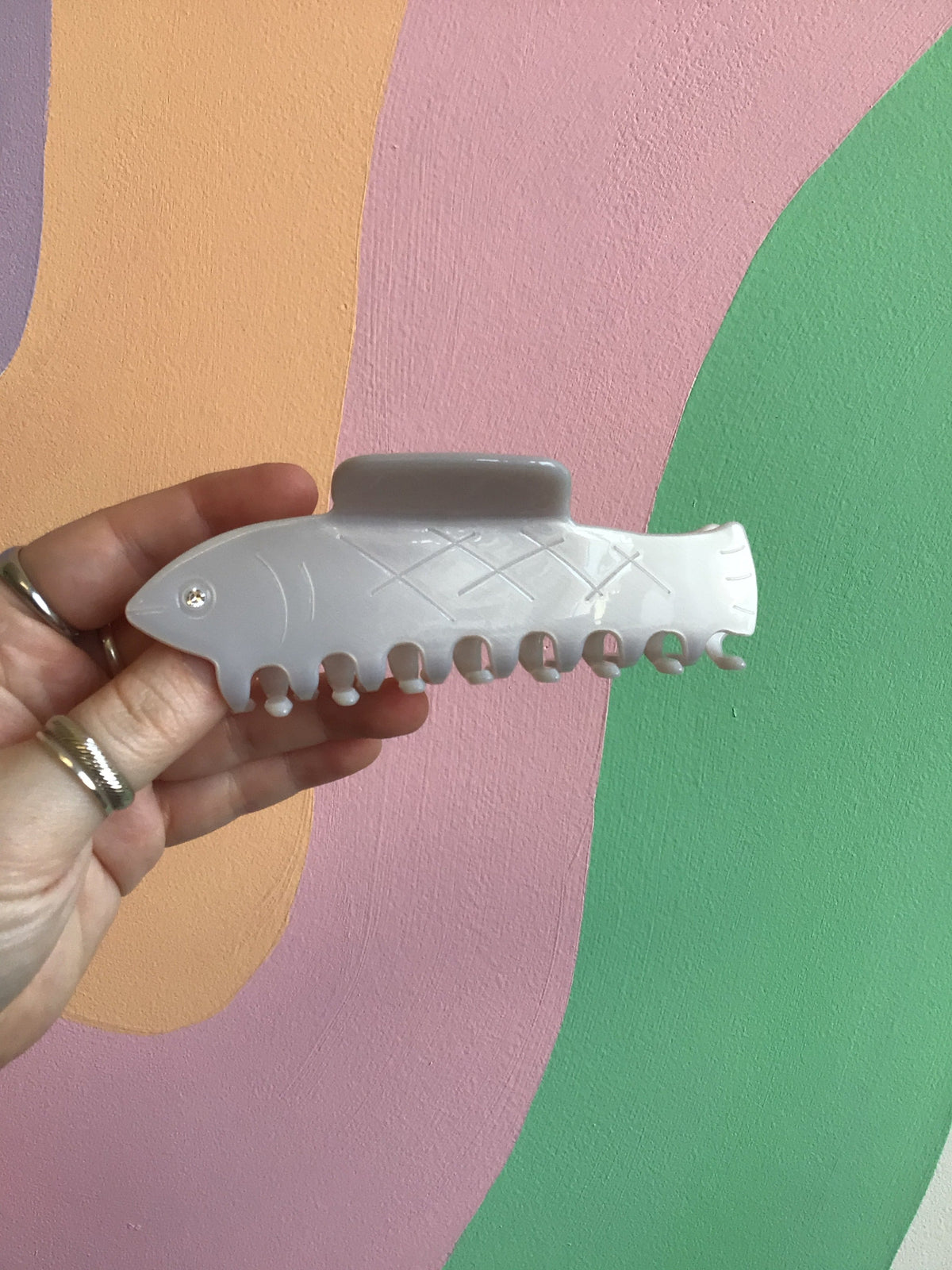 White fish-shaped hair claw with scalloped teeth and small silver pin details