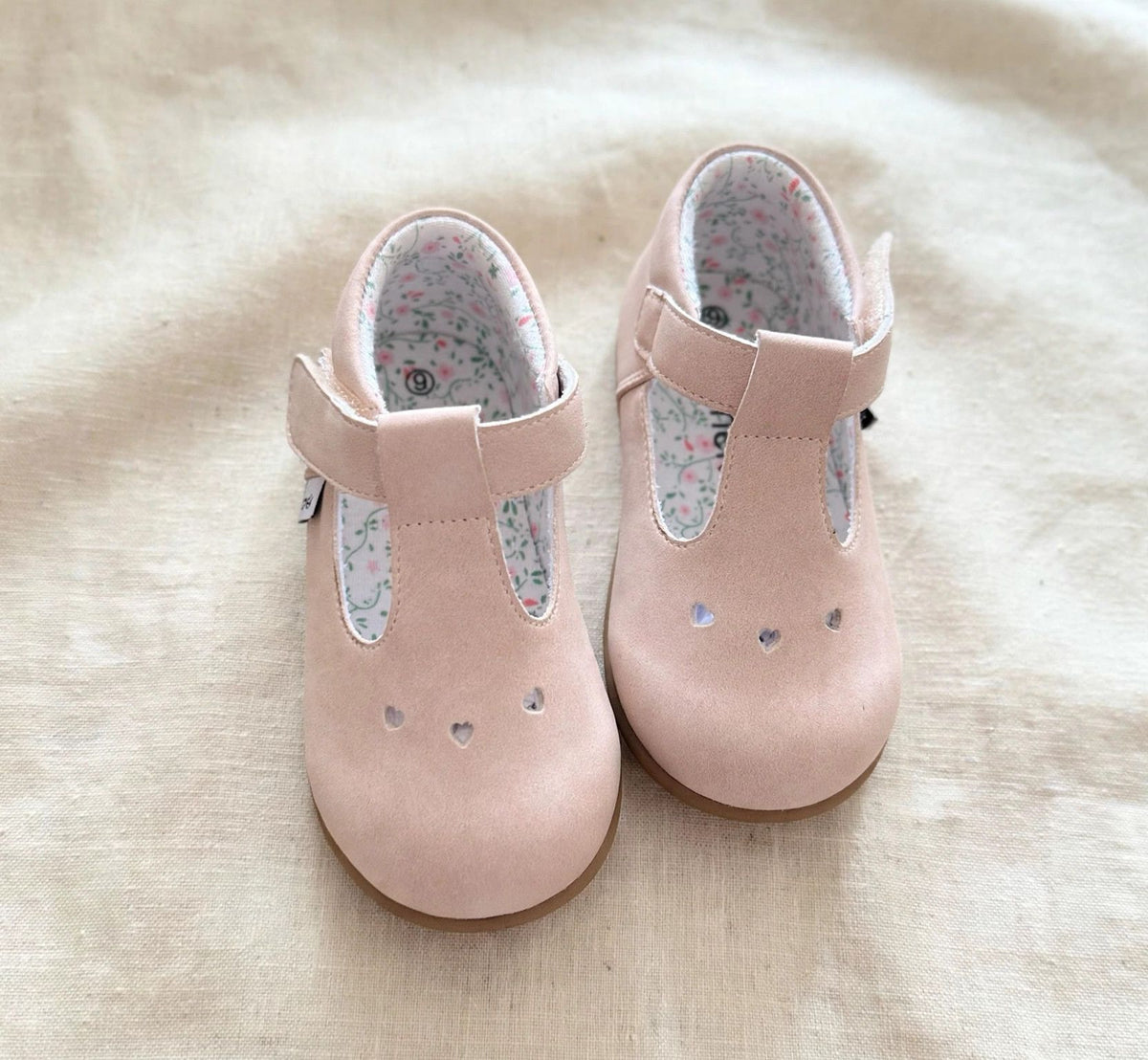Front view of blush pink kids Mary Jane slip-on shoes with heart studs