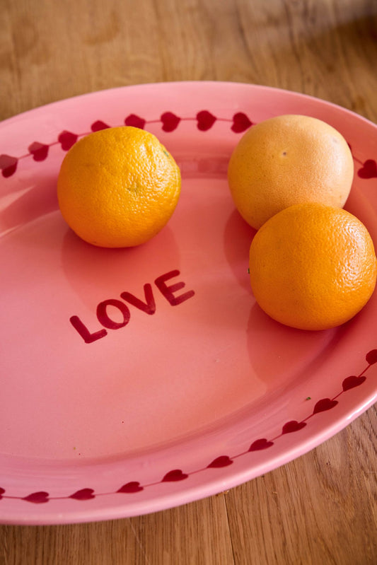 Pink ceramic serving platter with red hearts, LOVE text, and three orange fruits