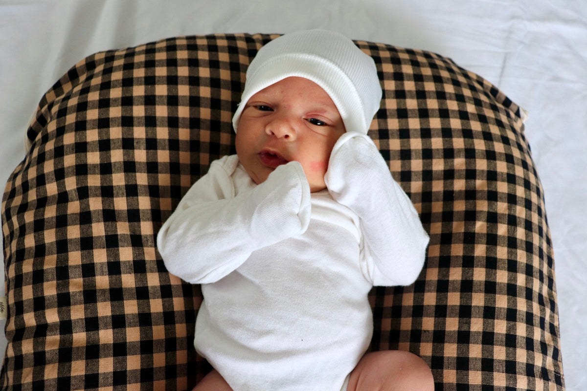 Brown and black gingham lounger cover shown behind a baby