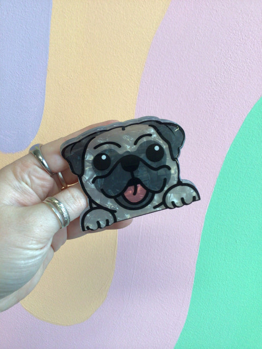 Black pug dog hair claw with smiling face, held in hand
