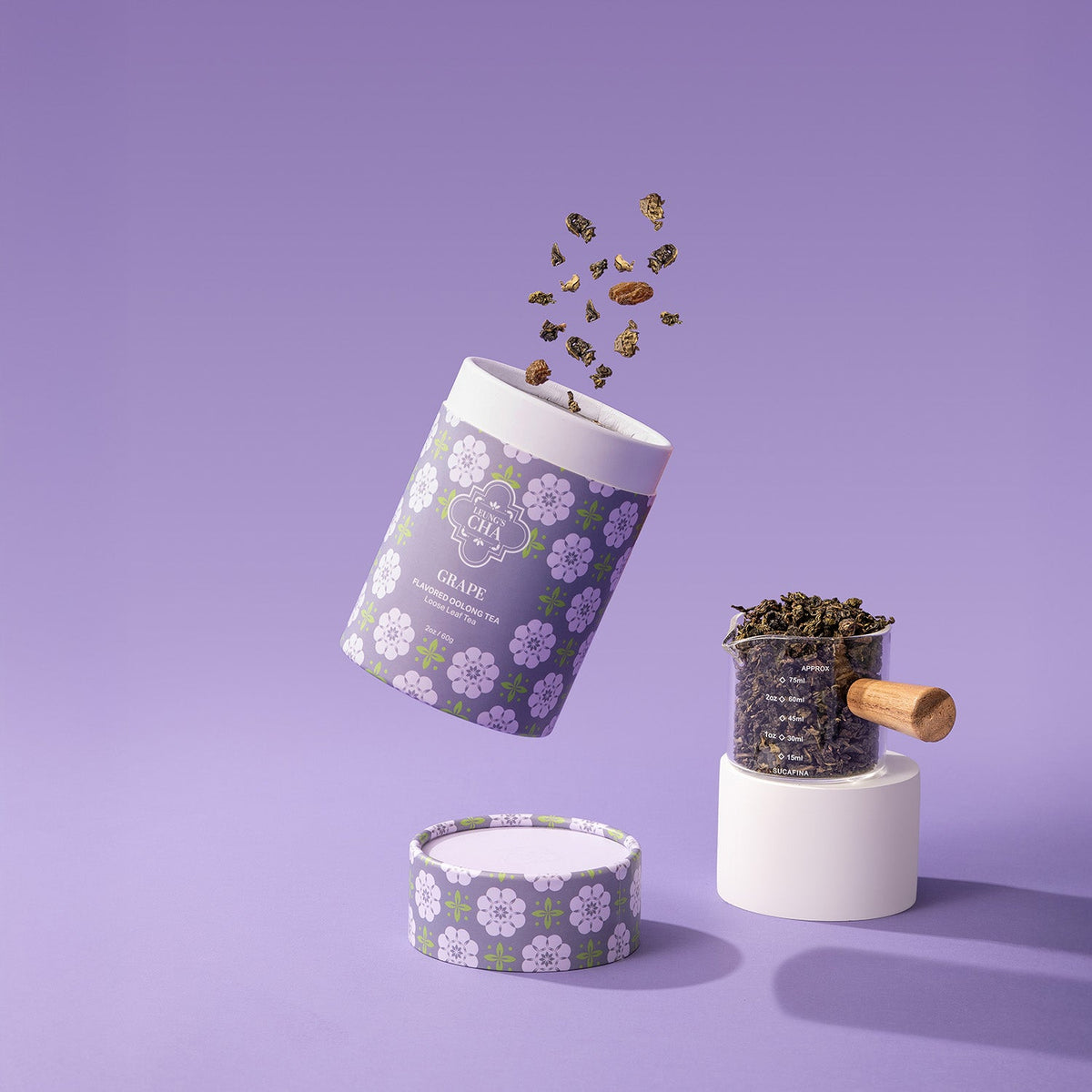Flavored oolong tea canister with grape floral design; loose tea leaves scattered