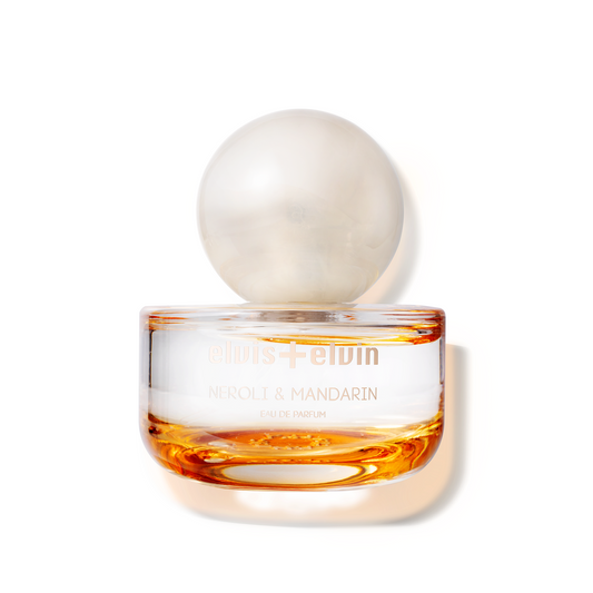 Neroli & mandarin eau de parfum bottle with round glass cap and amber liquid