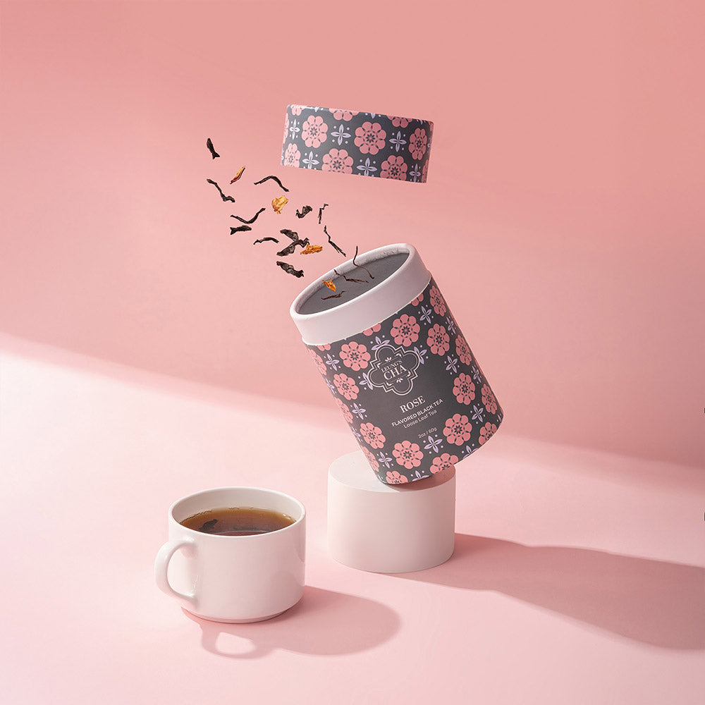 Rose tea tin with patterned sides next to a cup of brewed tea