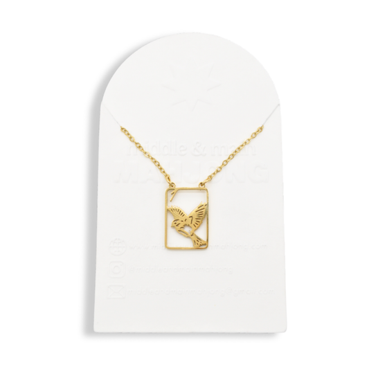 Gold necklace with square bird pendant on display stand