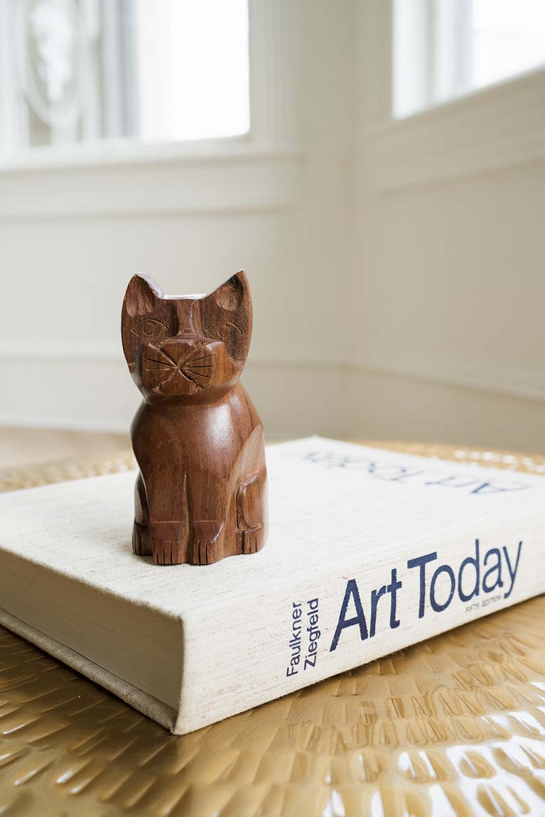 Hand-carved wooden cat eyeglass holder stand, warm brown, seated with carved face.