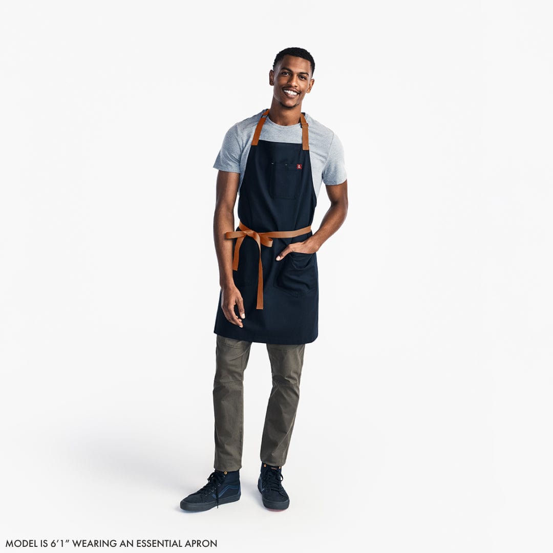 Navy floral apron worn with adjustable waist ties and neck strap, two front pockets