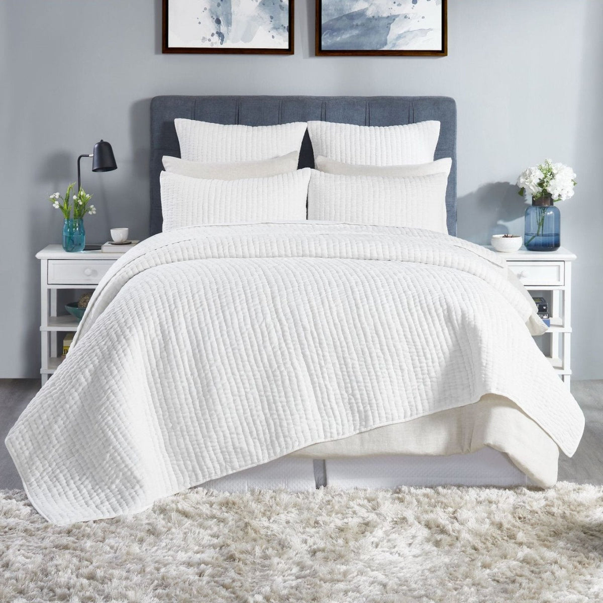 White stone-washed cotton quilt with textured weave, draped on bed.