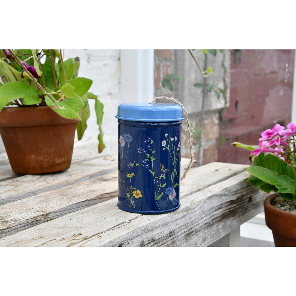 Decorative blue twine tin with blue lid, floral print, and gold string handle