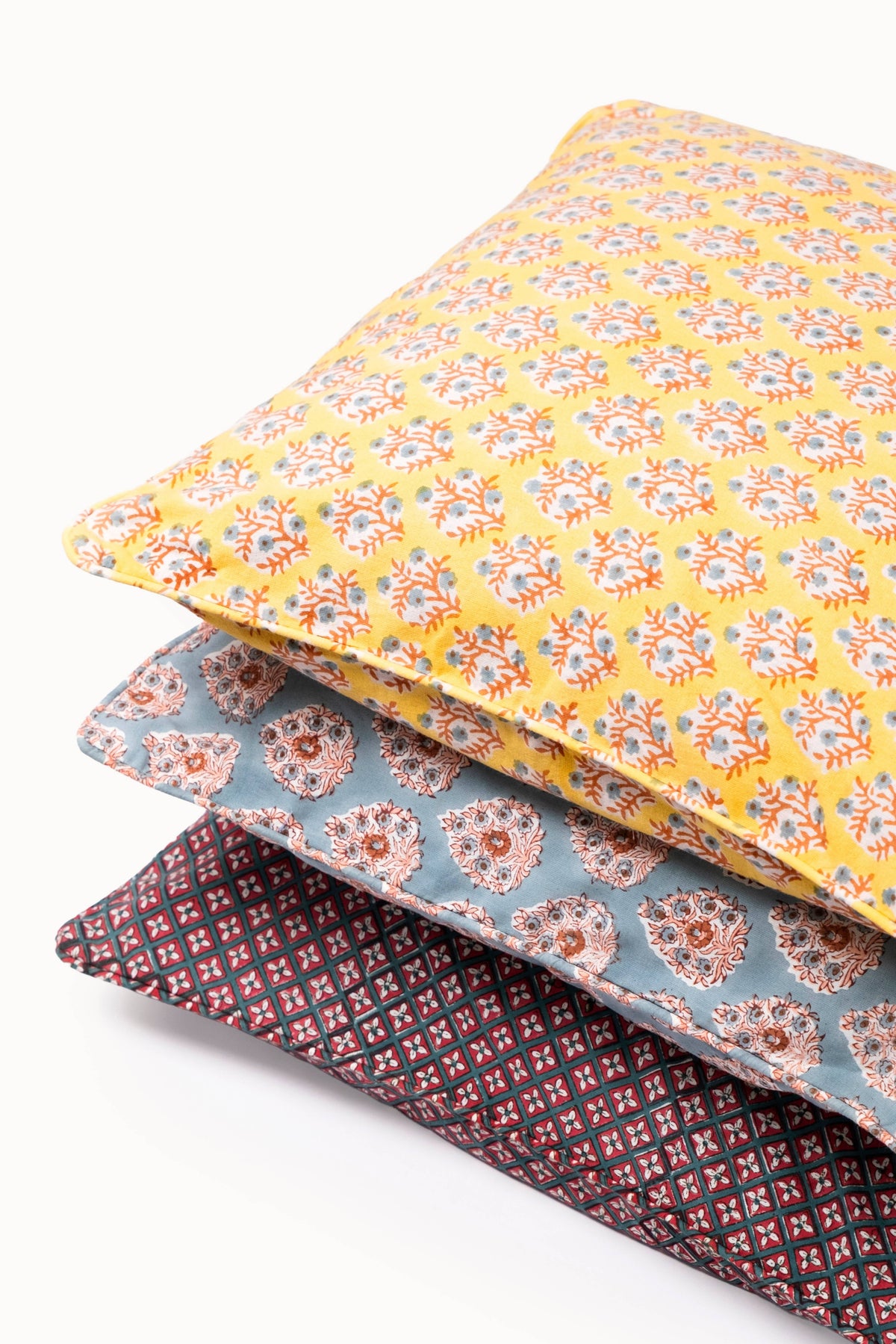 Stacked pillows featuring a crimson diamond-pattern cover with dark piping
