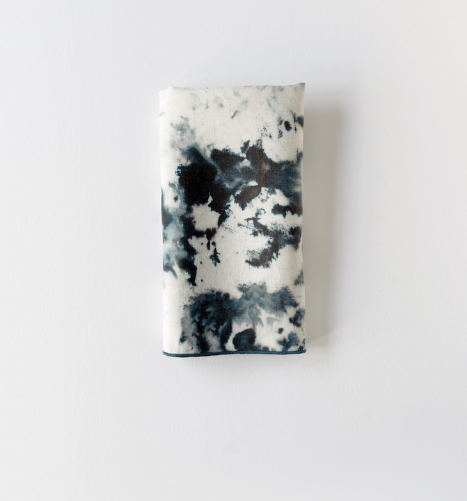 Marble-print napkin with dark blue-gray blotches on light fabric, no trim shown
