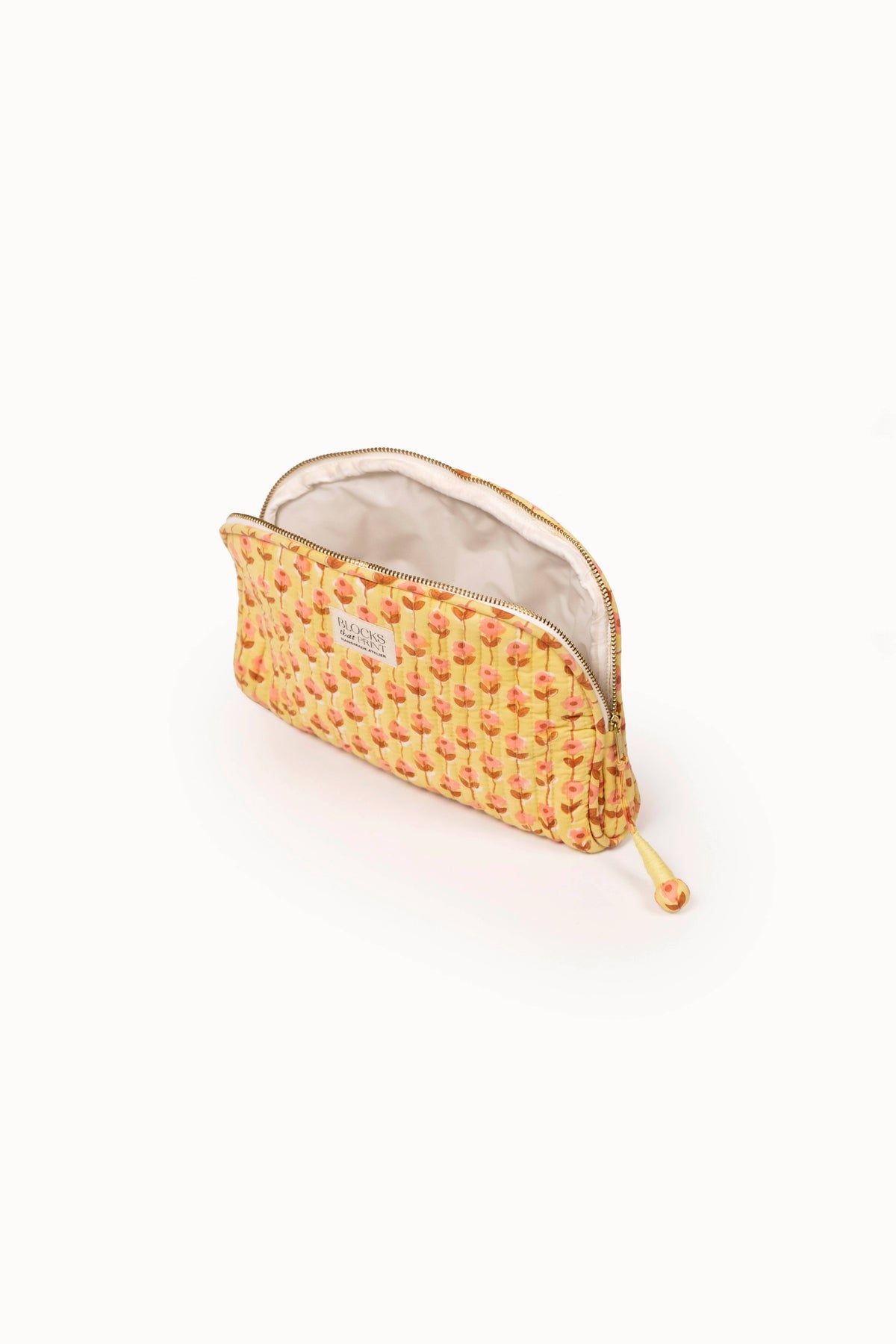 Quilted medium travel pouch with orange floral block print, open zip top and beige lining.