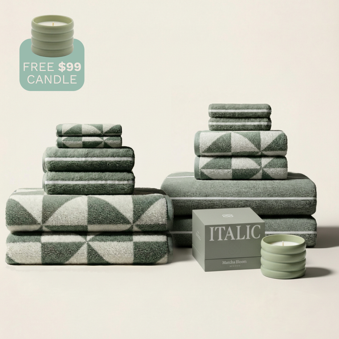 Green and ecru patterned cotton towels set stacked with candles and labels cropped out