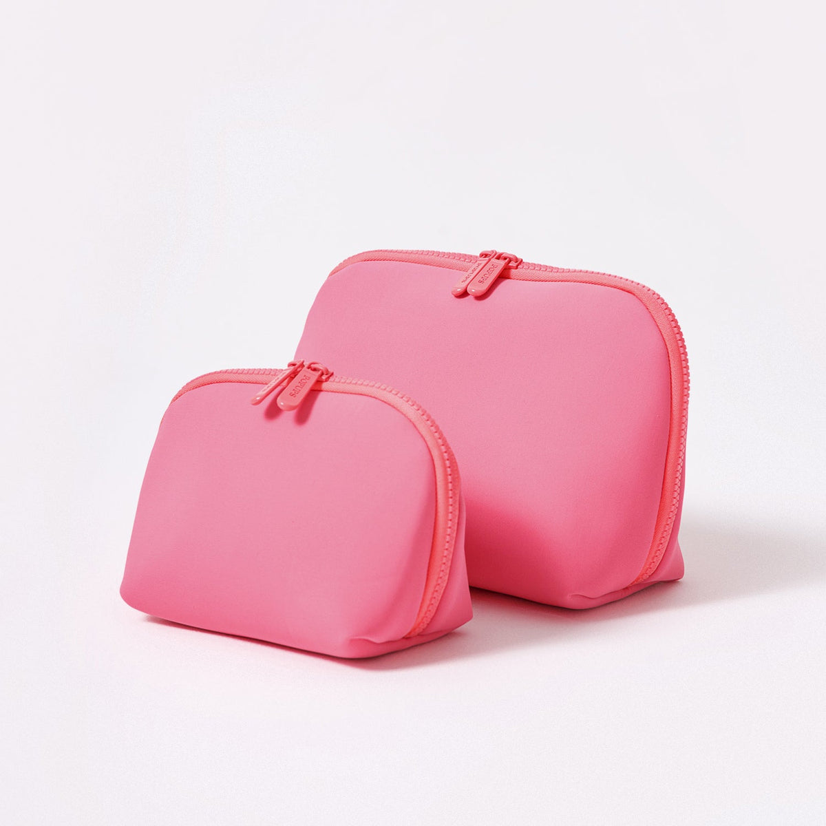 Neon pink makeup pouch set with two zippered pouches and heart logo detail