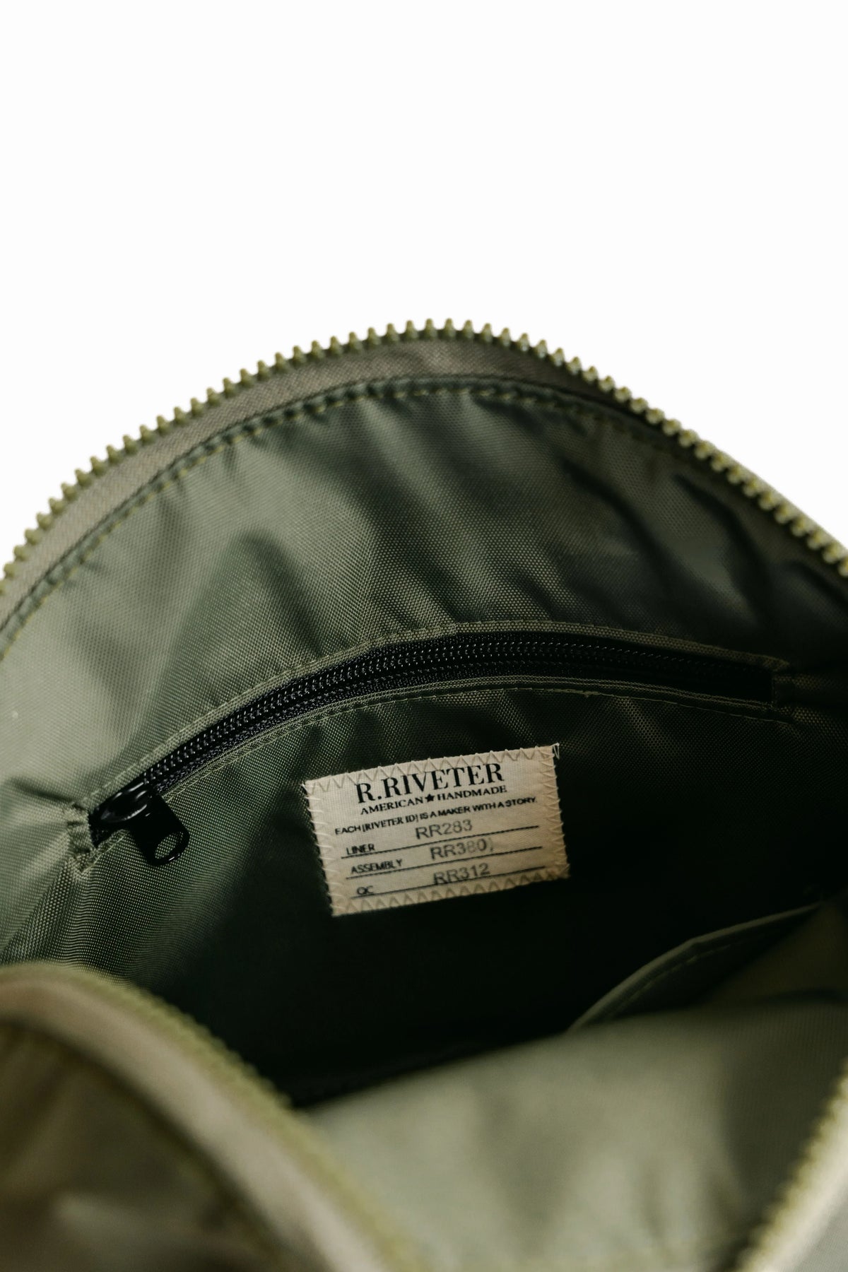 Olive nylon bag interior with visible zipper and RIVETER label
