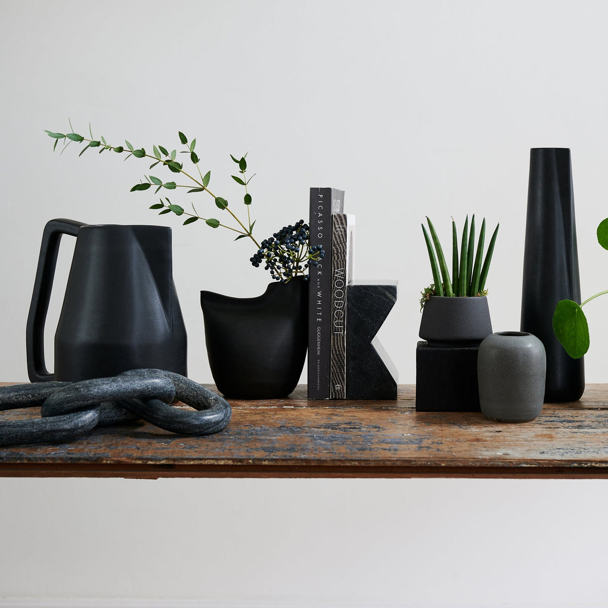 Assorted matte black vases with different shapes, including a handled bird vase.