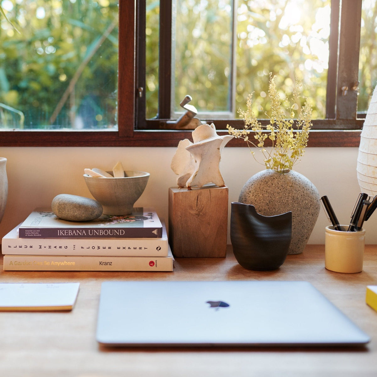 Black bird-shaped vase on desk beside books and small flowers