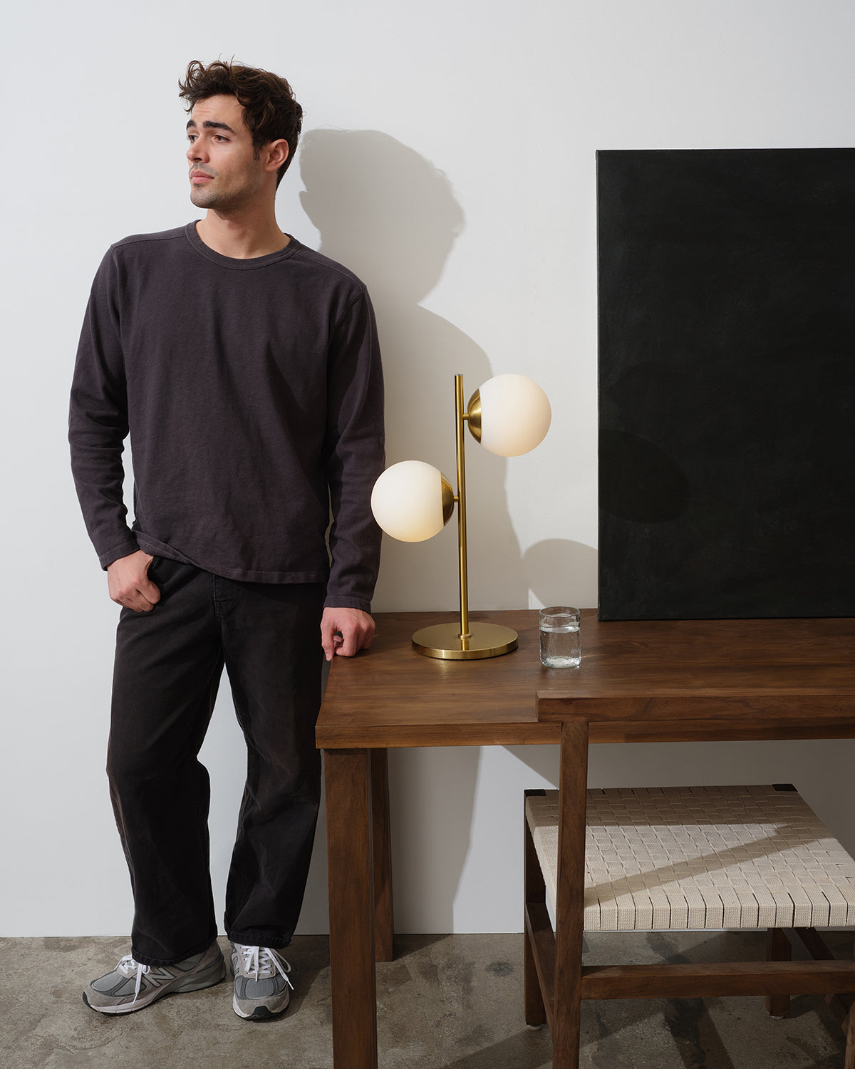 Two-globe table lamp with white shades and gold brass stem on wooden console table