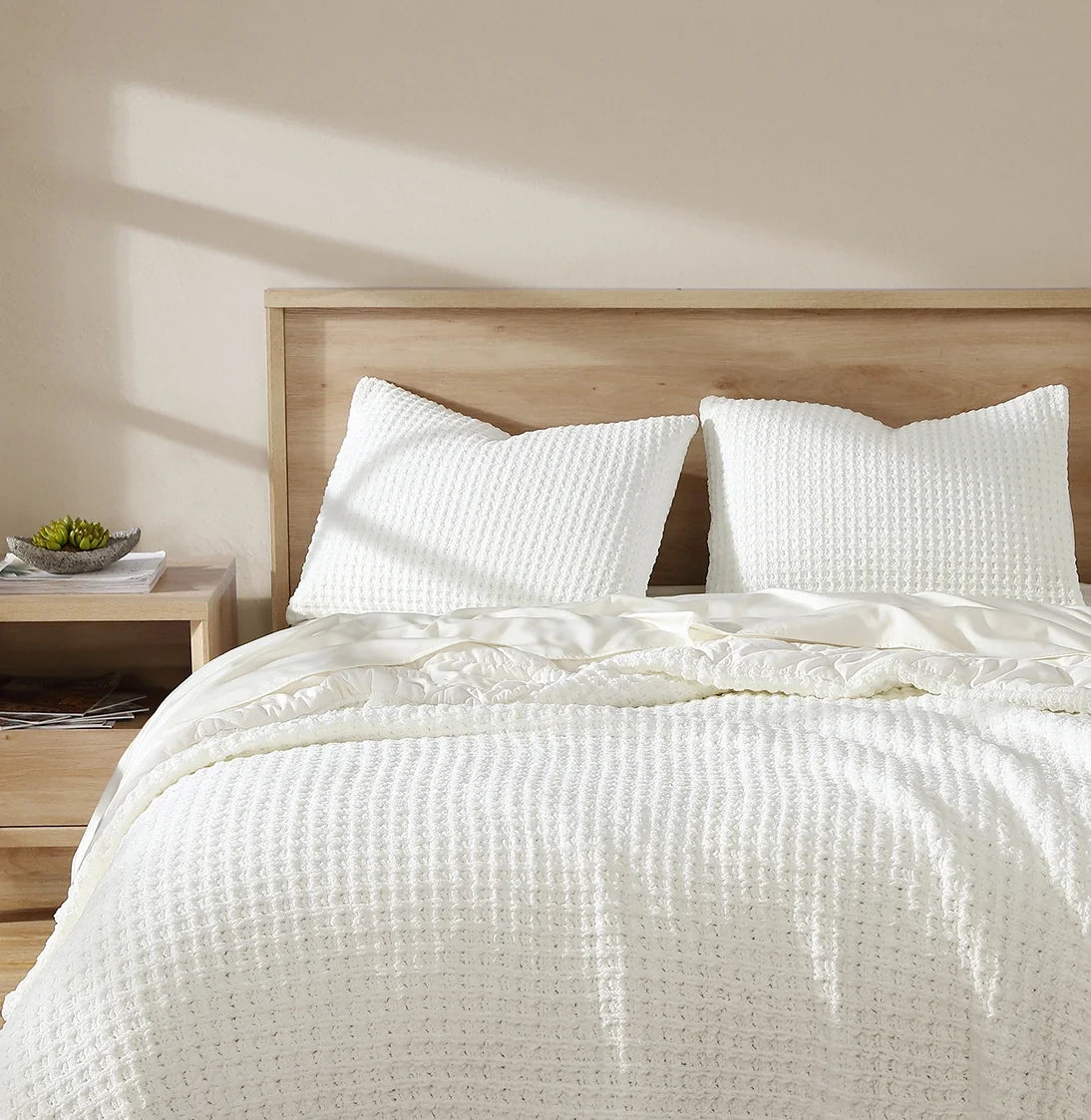 Off-white waffle comforter on bed with two matching square shams
