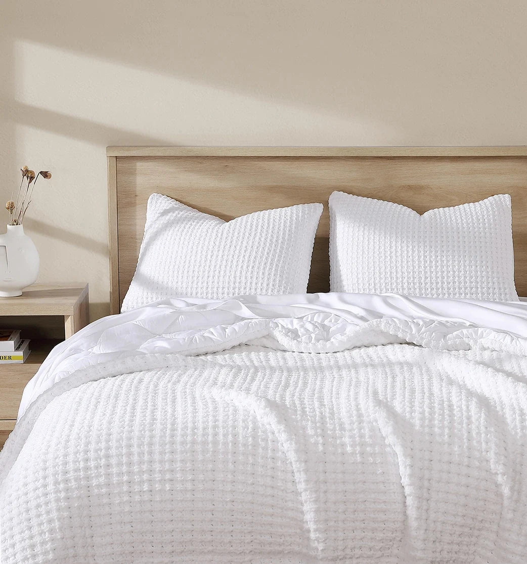 White waffle comforter with two textured square shams on a bed