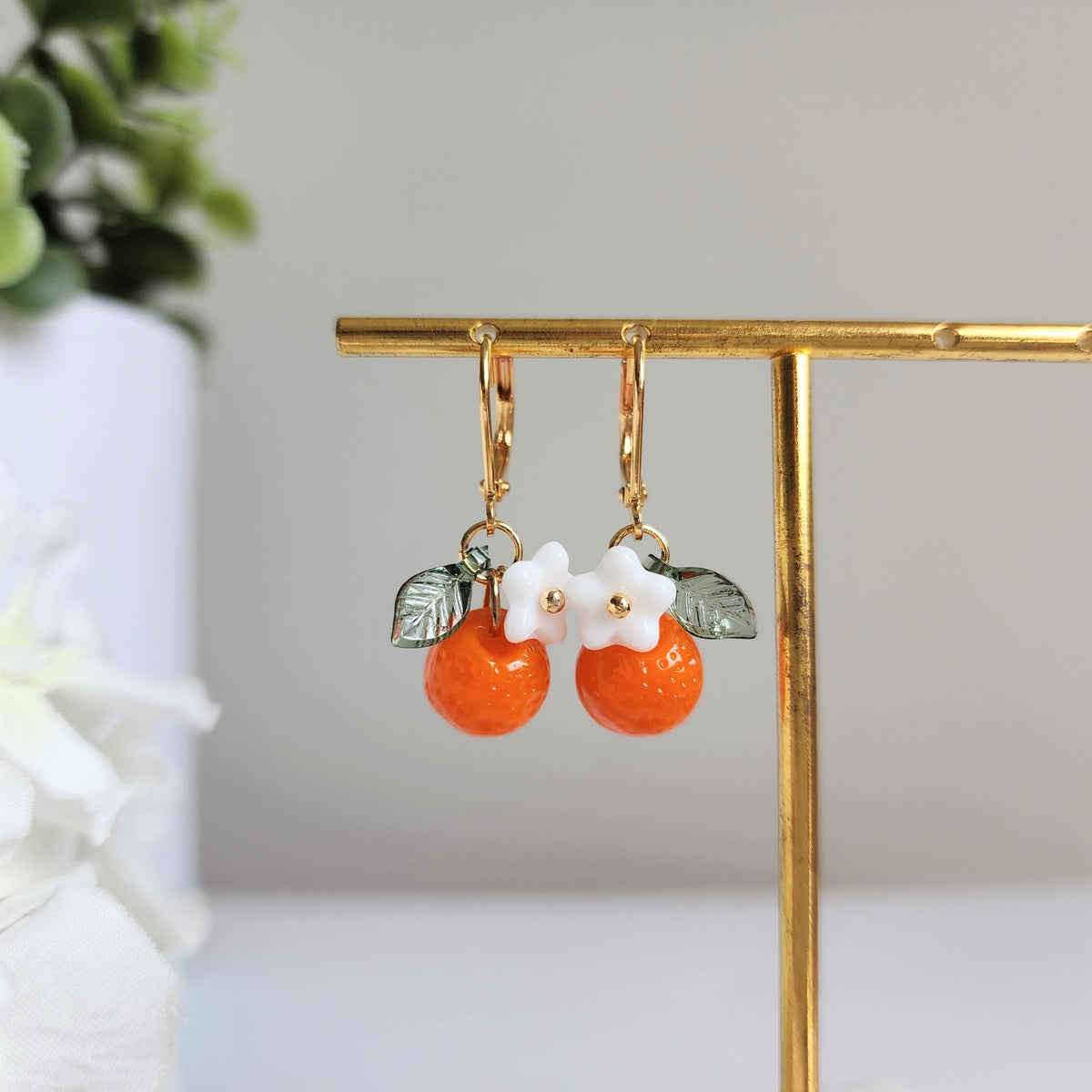 Orange fruit dangle earrings with white flower and green leaf, gold hooks