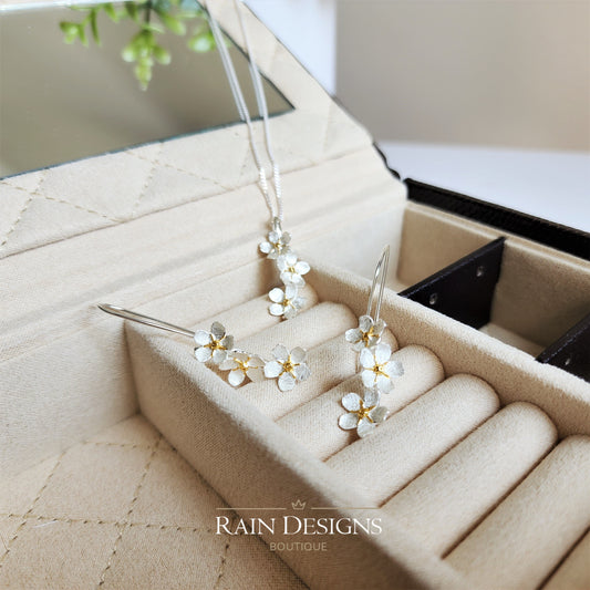 Silver forget-me-not flower necklace with matching floral stud earrings set on display tray.