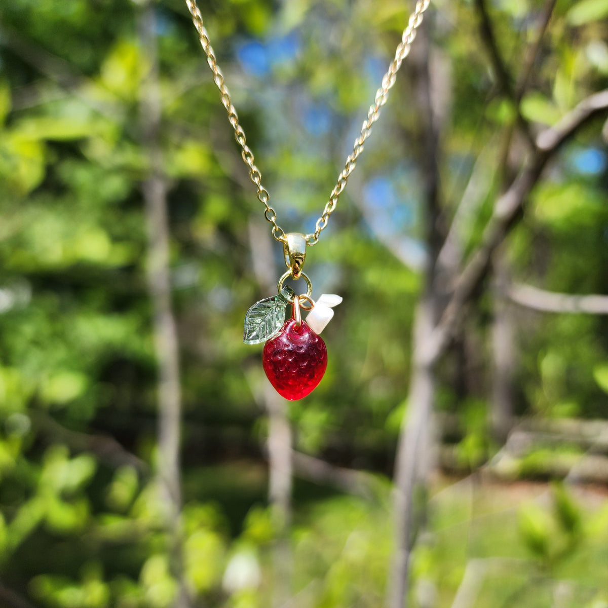 Gold mini strawberry pendant necklace with dangling white flower and green leaf