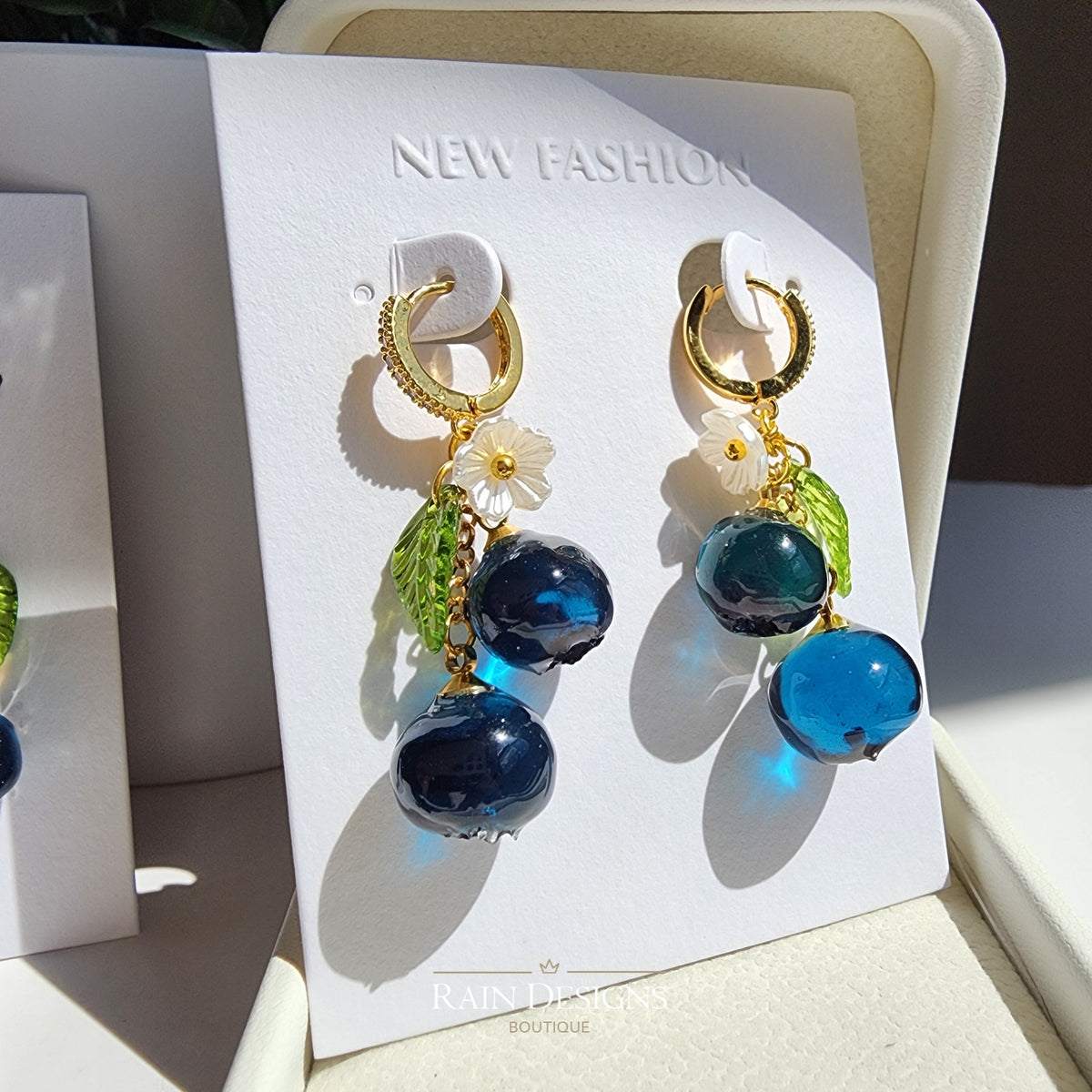 Blueberry cluster dangle earrings with blue resin berries, green leaves, and gold hoop hooks
