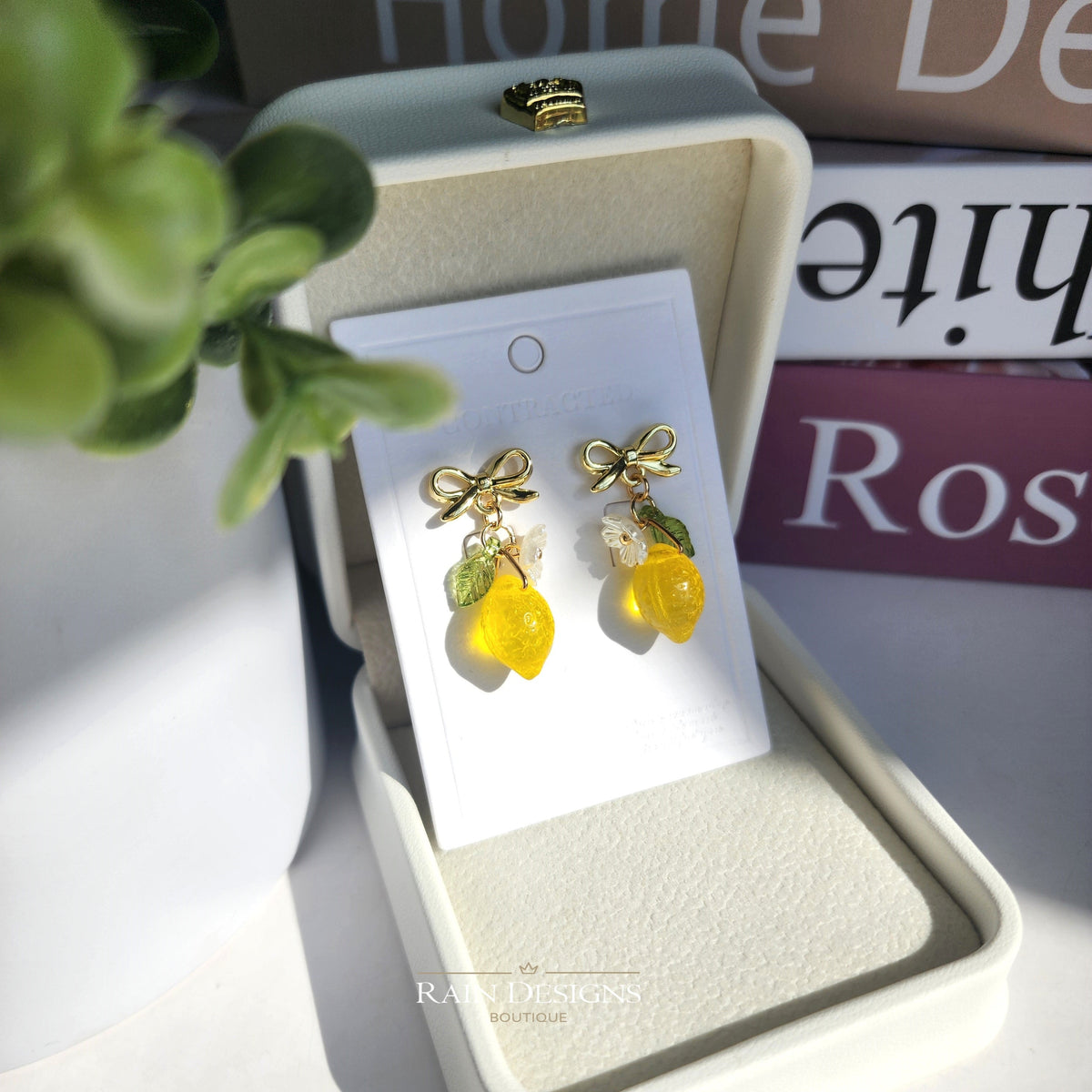 Gold lemon dangle earrings in jewelry box: yellow charms, green leaves, and bow accents