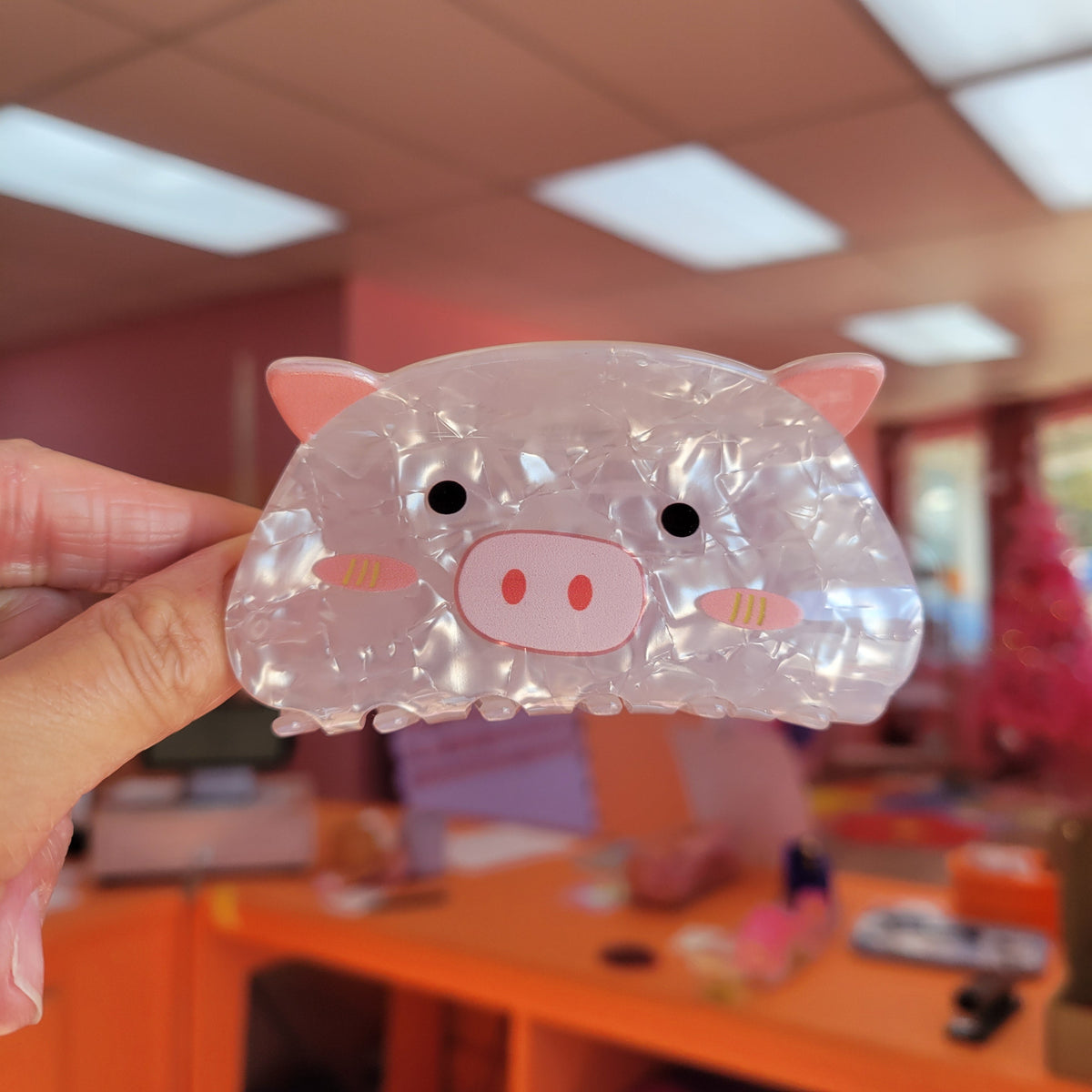 Clear animal hair claw with pink pig face, ears, and shiny iridescent finish