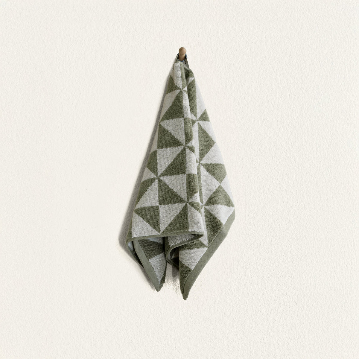 Folded green and ecru geometric cotton towel on a hanging loop