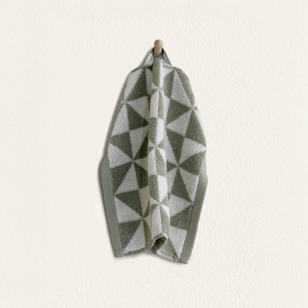 Green and ecru geometric cotton towel draped with visible plush pile