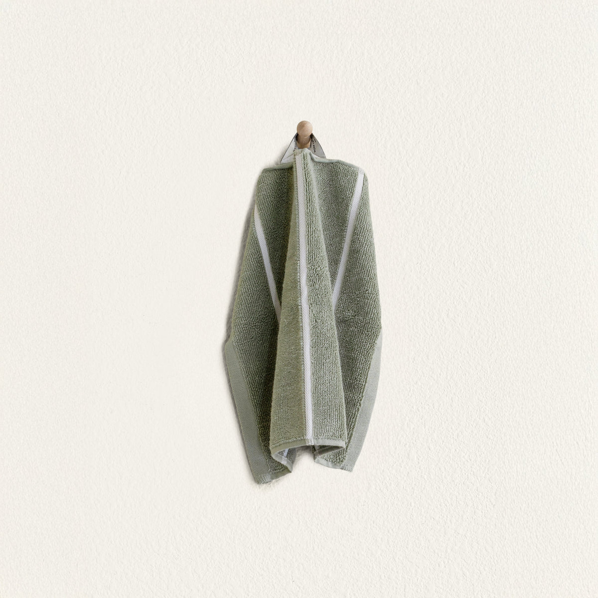 Sage green cotton towel with white vertical stripe, folded and hanging