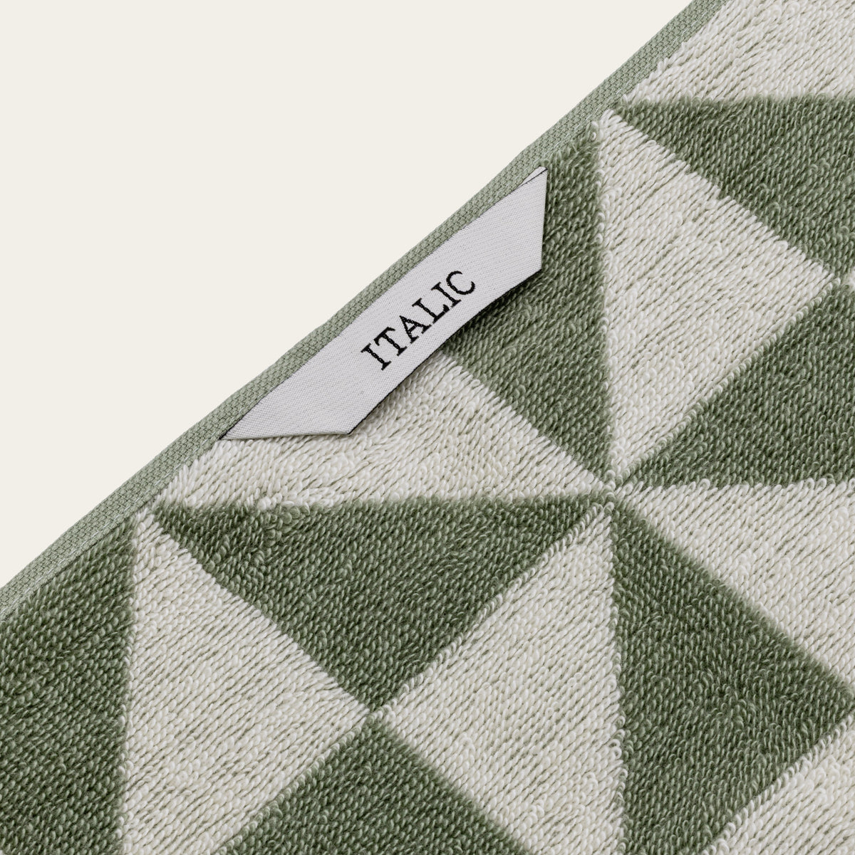 Close-up of ITALIC label on green and ecru geometric cotton towel border