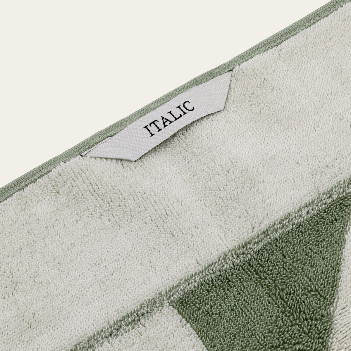 Close-up of green and ecru geometric cotton towel label reading ITALIC