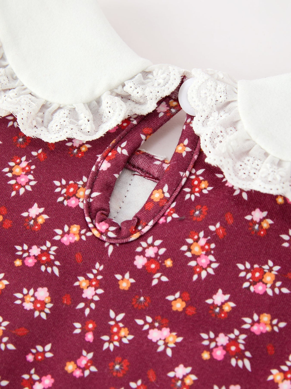 Burgundy floral dress close-up: white scalloped lace collar and tied neckline