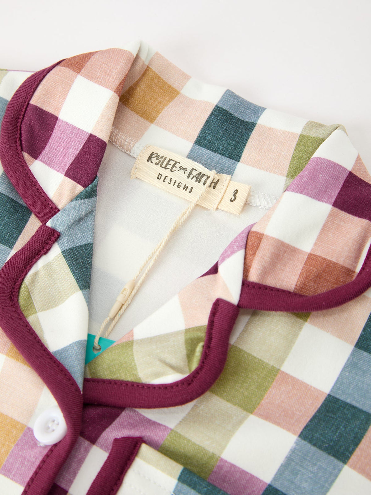 Plaid pajama top detail with maroon-trim neckline and buttoned placket, close-up