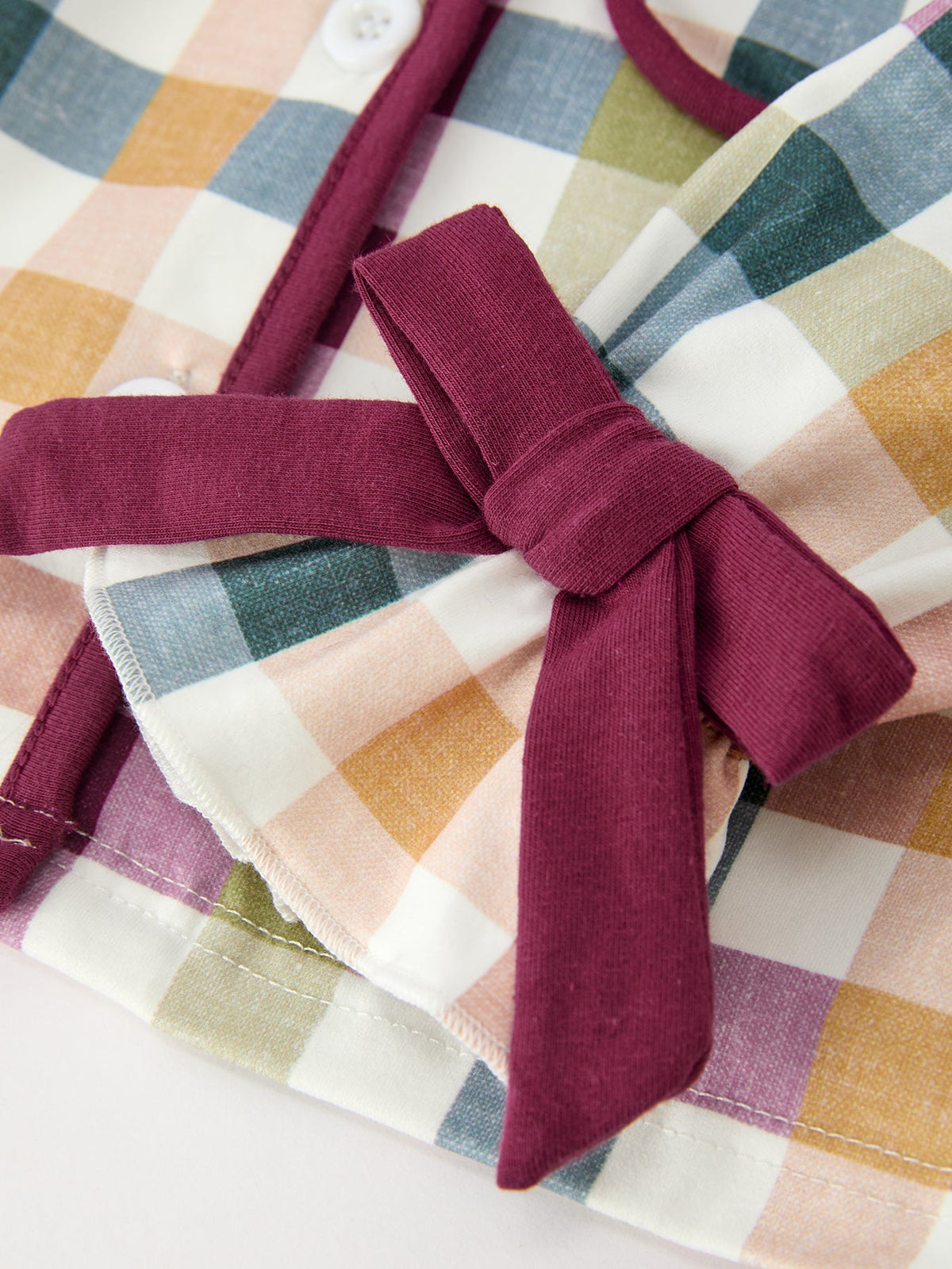 Plaid pajama top with maroon bow tie detail at chest, close-up