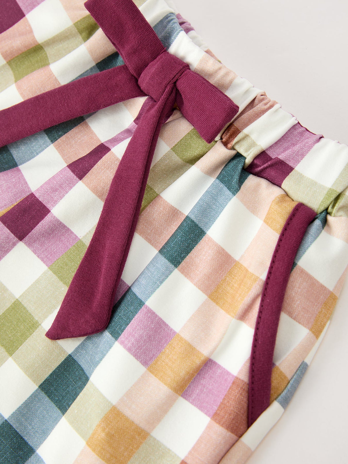 Plaid pajama shorts with maroon tie belt and elastic waist, front close view