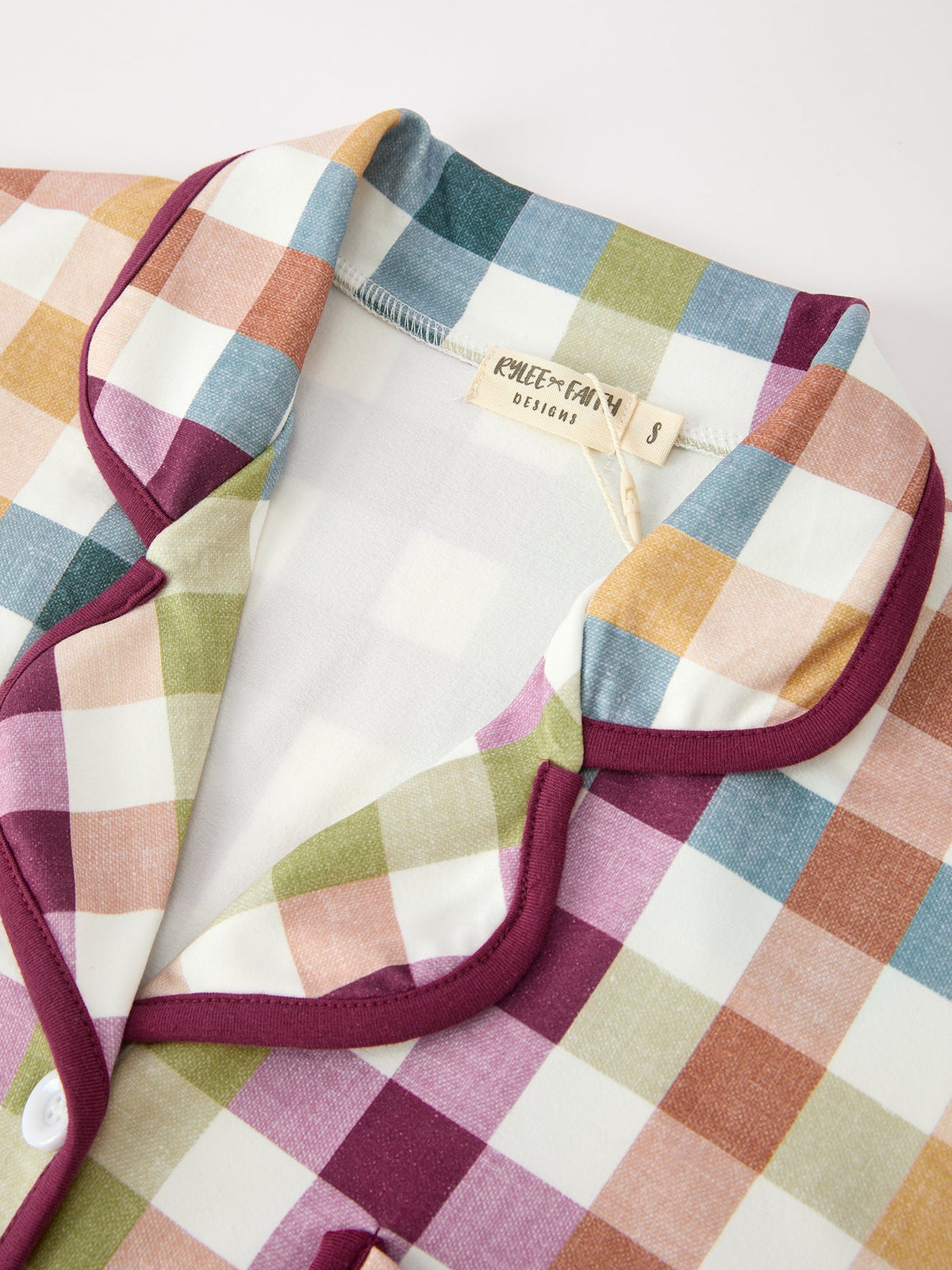 Plaid pajama top neckline and pocket detail with maroon trim and brand tag