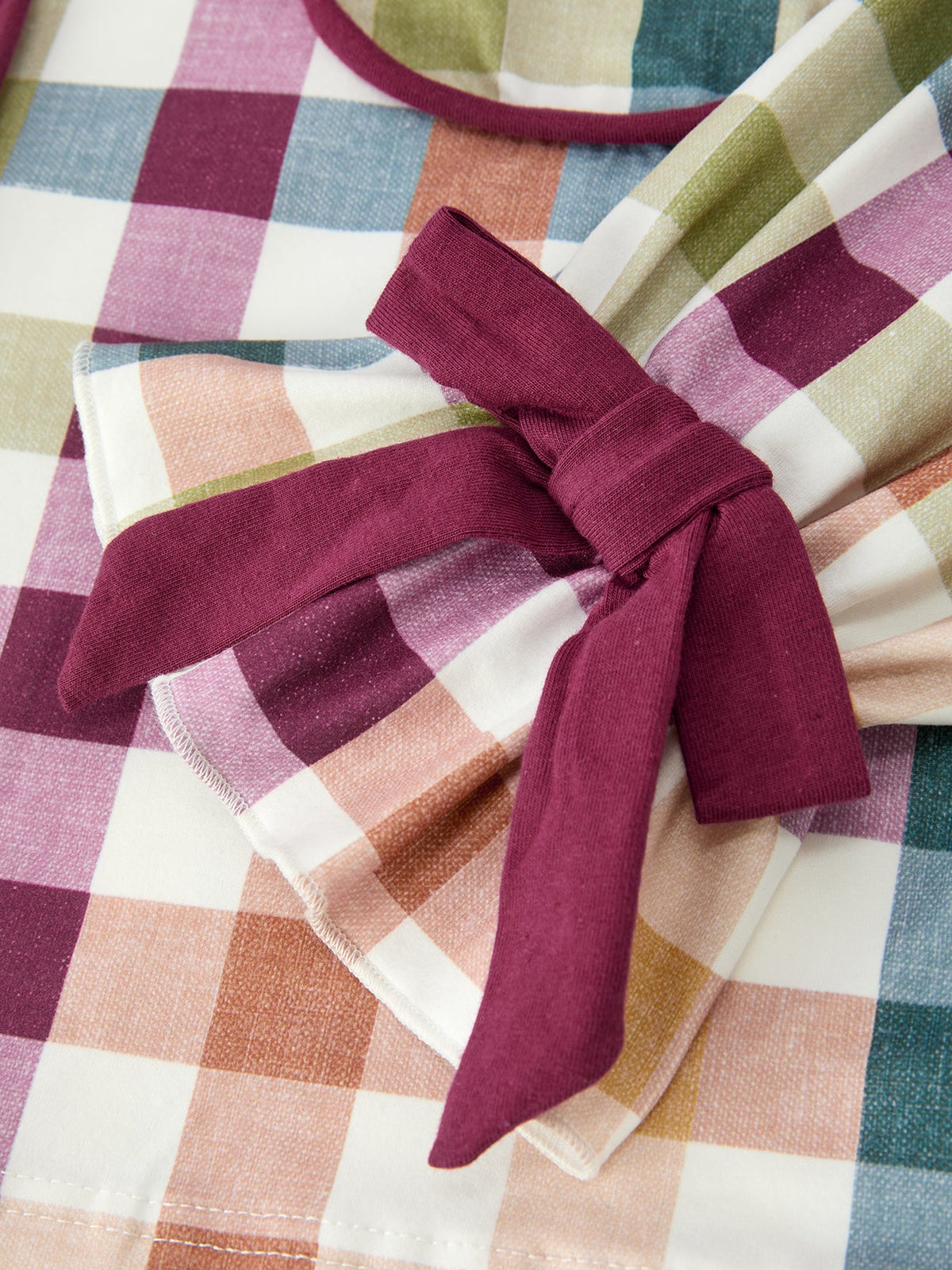 Plaid pajama top with maroon neck tie bow, buttons at collar, close-up