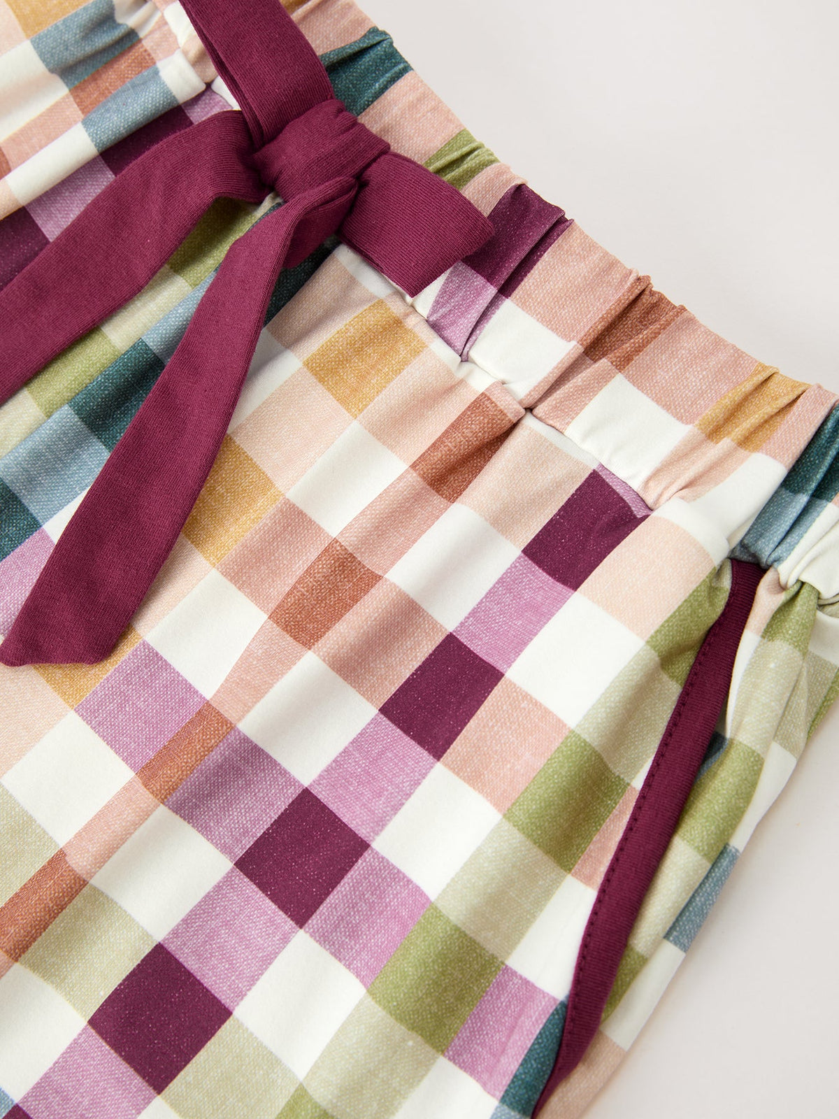 Plaid pajama shorts with maroon side trim and elastic waistband, close-up