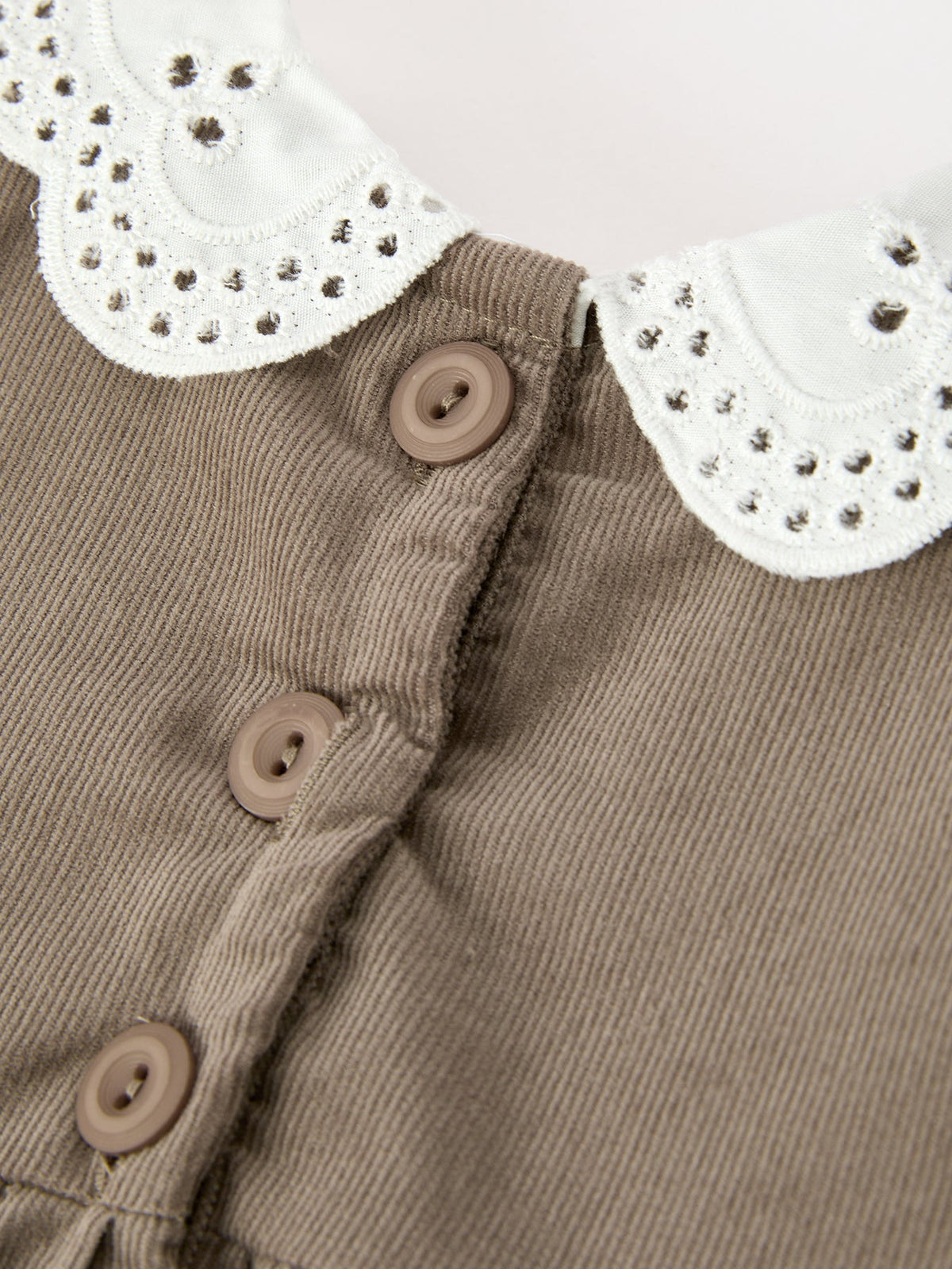 Taupe romper front with three tan buttons and white eyelet collar applique
