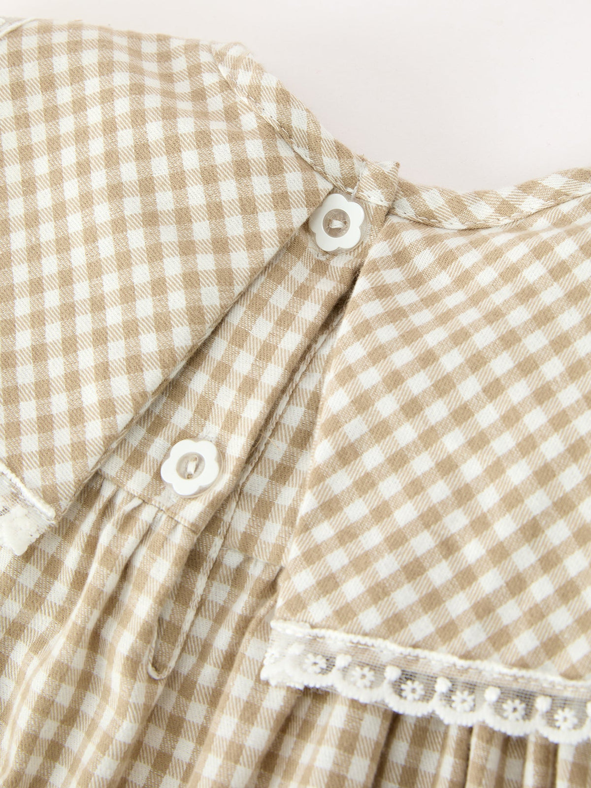 Girls gingham plaid dress detail with buttoned shoulder and white lace-trim bib