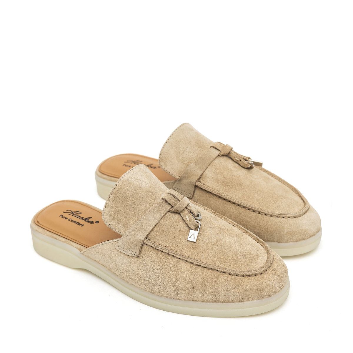 Pair of beige suede mules with apron toes, metal charms, and tan insoles