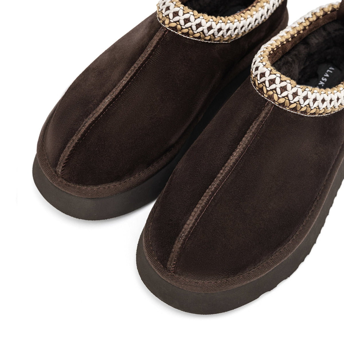 Close-up of brown suede slipper uppers with center seams and braided trim