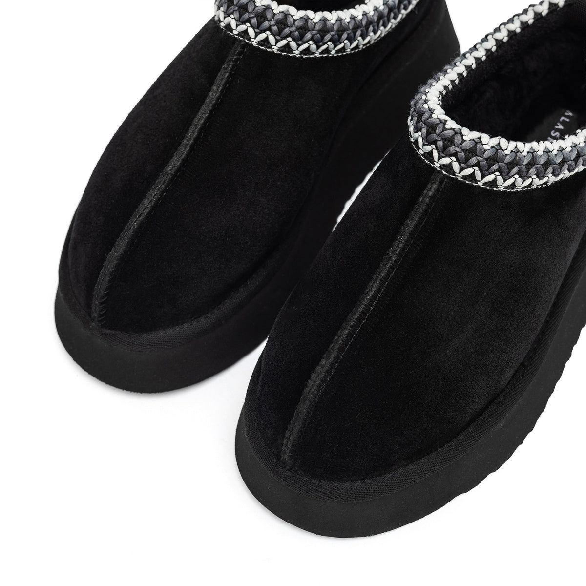 Close-up of black slipper toes, plush lining, and braided trim