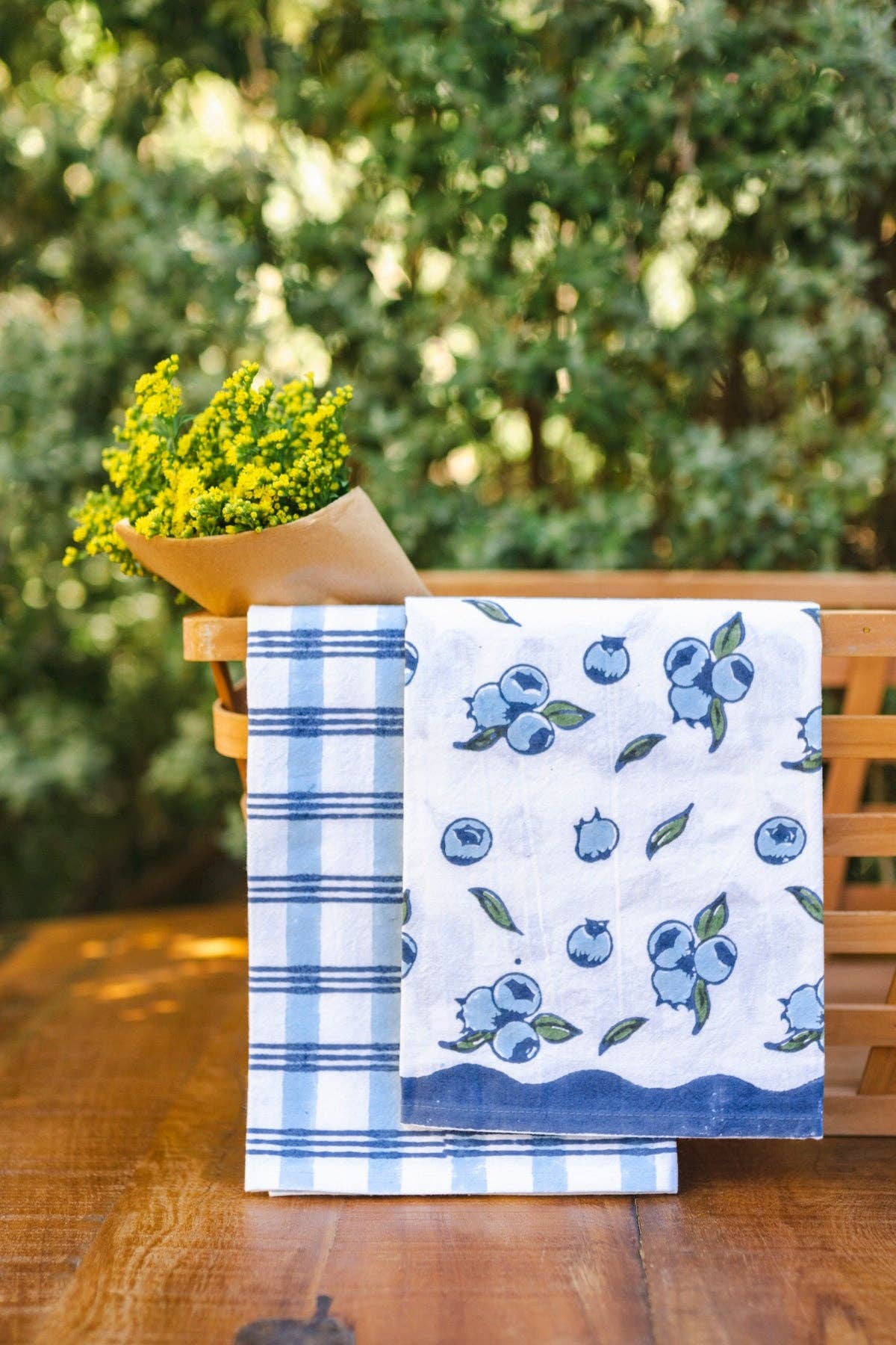 Blueberry tea towel, white with blue berry and leaf pattern, folded with blue stripes